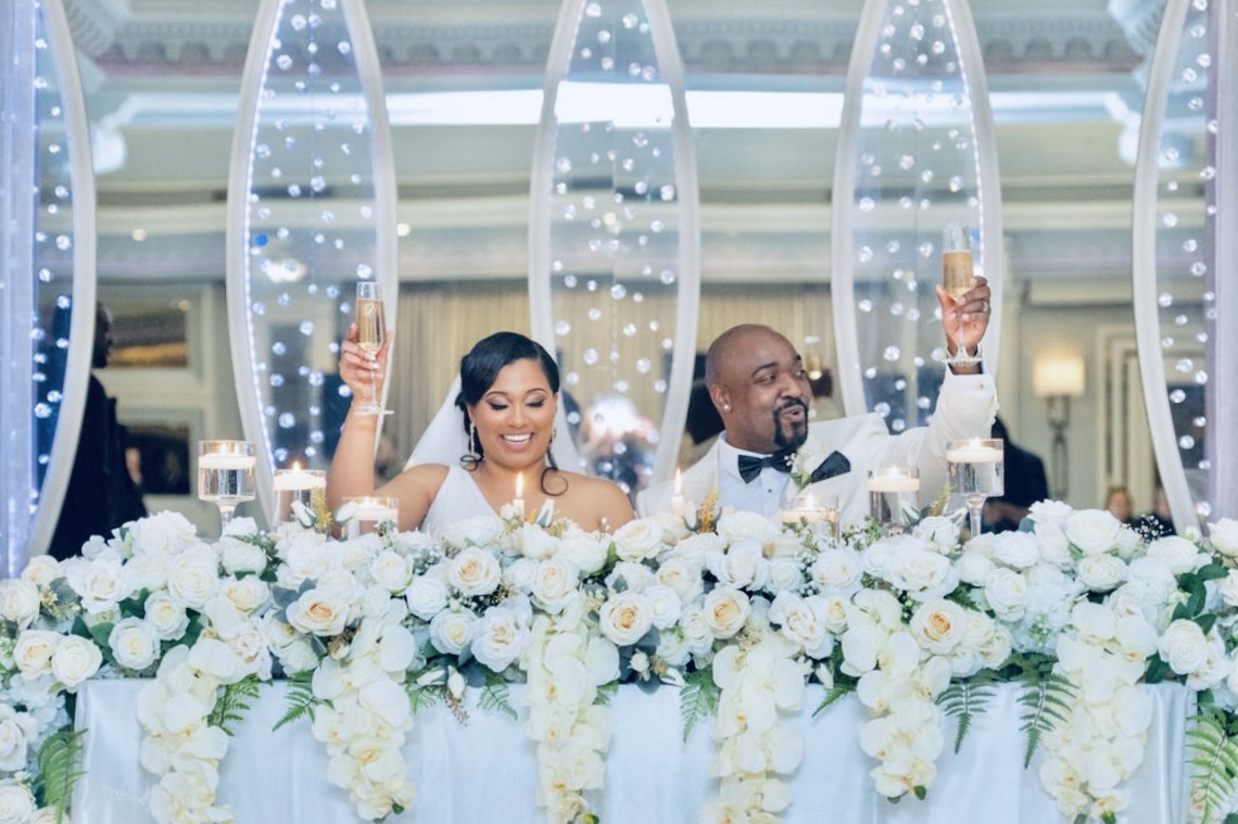 Luxury wedding head table floral installation and celebration toast